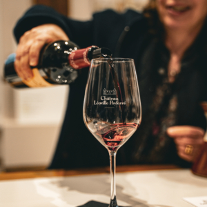 Picture of a woman serving a glass of red wine from the Château Léoville Poyferré, the second Classified Grand Cru of Saint-Julien.